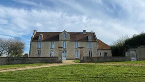 A large stone building with a symmetrical facade, multiple windows, and a central entrance.