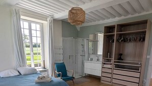 A bedroom with a bed, a chair, a wardrobe, and a hanging light fixture.