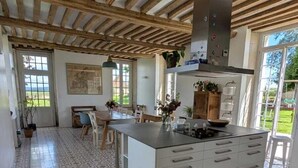 A spacious kitchen with a large island, wooden beams on the ceiling, and patterned floor tiles.