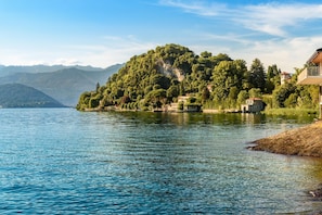A lake with a forested island and houses on the right. - Casa Amabile With Pool (Leggiuno)