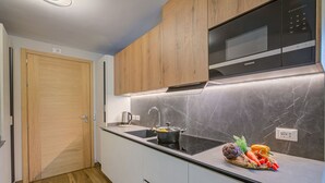 Una cocina moderna con armarios de madera, un microondas negro y un salpicadero de mármol.