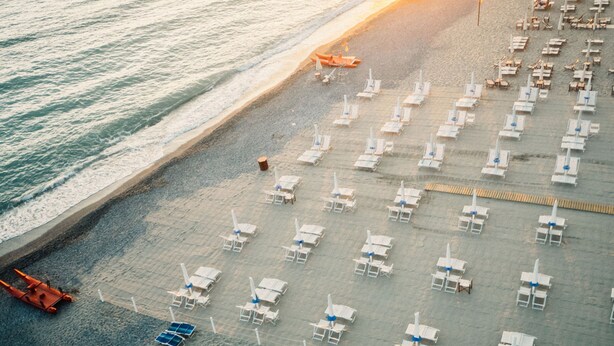An aerial view of a beach with rows of sun loungers and umbrellas, a lifeguard tower, and a small boat. - Ardenza s Aires 600 Mt From Sea (Livorno)