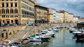 A marina with boats docked along a stone quay, surrounded by historic buildings with classical architecture. - Ardenza s Aires 600 Mt From Sea (Livorno)