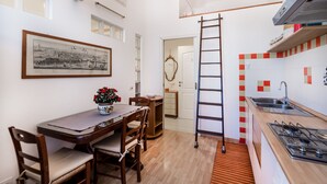 A compact kitchen with a wooden table, chairs, a ladder, and a tiled backsplash. - Ardenza s Aires 600 Mt From Sea (Livorno)