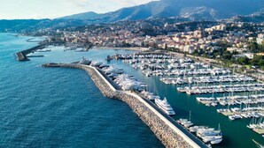 An aerial view of a marina with numerous boats docked, a stone quay, and a cityscape in the background. - Casa di Lella in Sanremo (Sanremo)