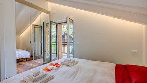 A hotel room with a bed, a red blanket, and a glass door leading to an outdoor area. - Cimetta in Livigno With 3 Bedrooms and 2 Bathrooms (Livigno)