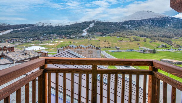 A balcony with a view of a mountainous landscape, a river, and a small town. - Cimetta in Livigno With 3 Bedrooms and 2 Bathrooms (Livigno)