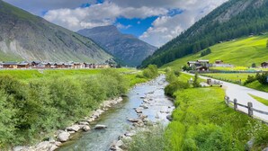 A mountain landscape with a river, houses, and a road. - Cimetta in Livigno With 3 Bedrooms and 2 Bathrooms (Livigno)