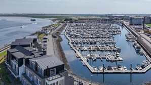 A marina with numerous boats docked, a waterfront building, and a clear sky. - Luxe apt VM - Havenweg 8-46 St-annaland (Sint-Annaland)