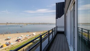 A balcony with a view of a beach and calm water. - Luxe apt VM - Havenweg 8-46 St-annaland (Sint-Annaland)