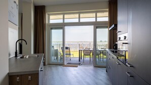 A modern kitchen with a large sliding glass door leading to a balcony with outdoor furniture. - Lux Apvm Lagunab-havenw 8-32 S-annaland (Sint-Annaland)