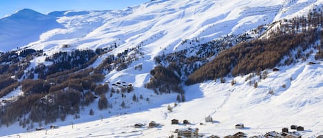 A snow-covered mountain with a ski resort and buildings in the foreground.
