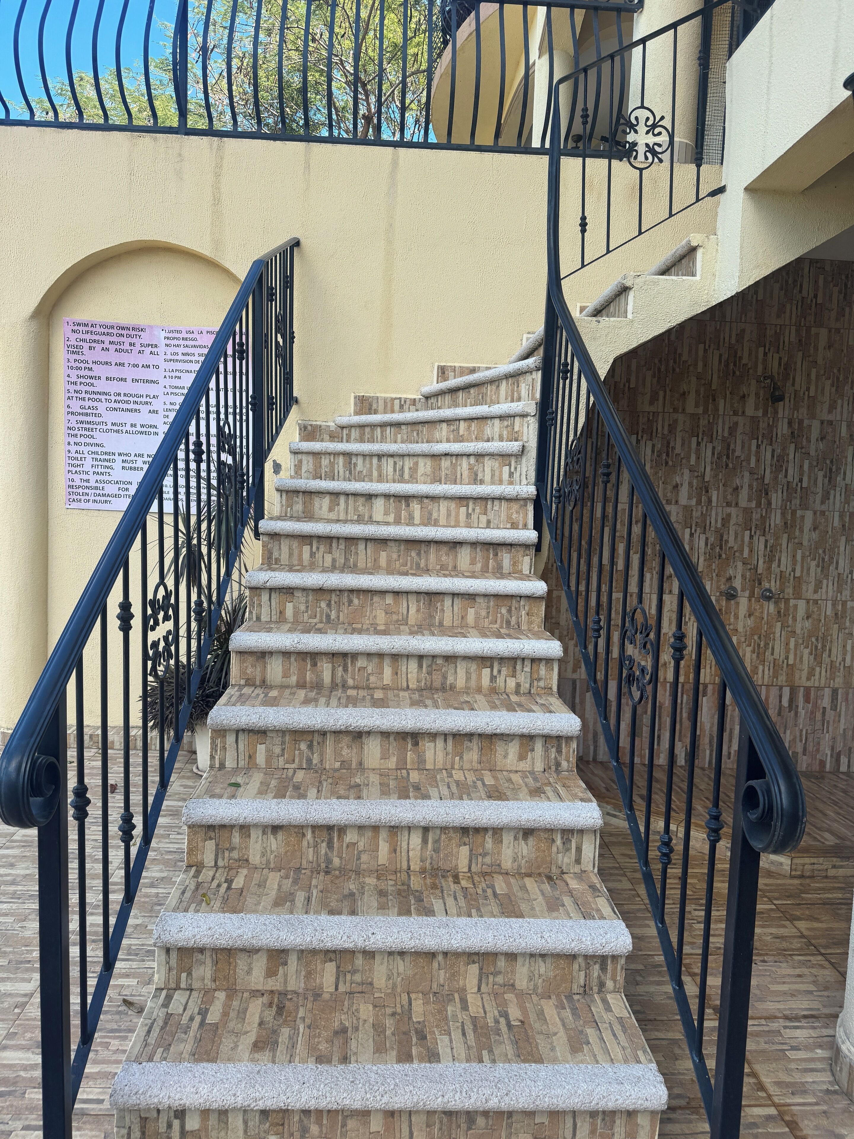 A staircase with stone steps and black metal railings, leading to an upper floor.