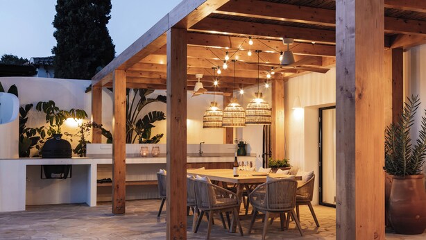 An outdoor dining area with a wooden pergola, stone flooring, and wicker chairs. - Fantastic family villa within walking distance to the beach! (Teulada)
