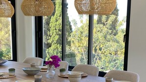 A dining area with a wooden table, white chairs, and woven pendant lights. - Fantastic family villa within walking distance to the beach! (Teulada)