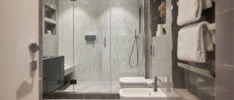 A modern bathroom with a glass-enclosed shower, a white sink, and a towel rack.