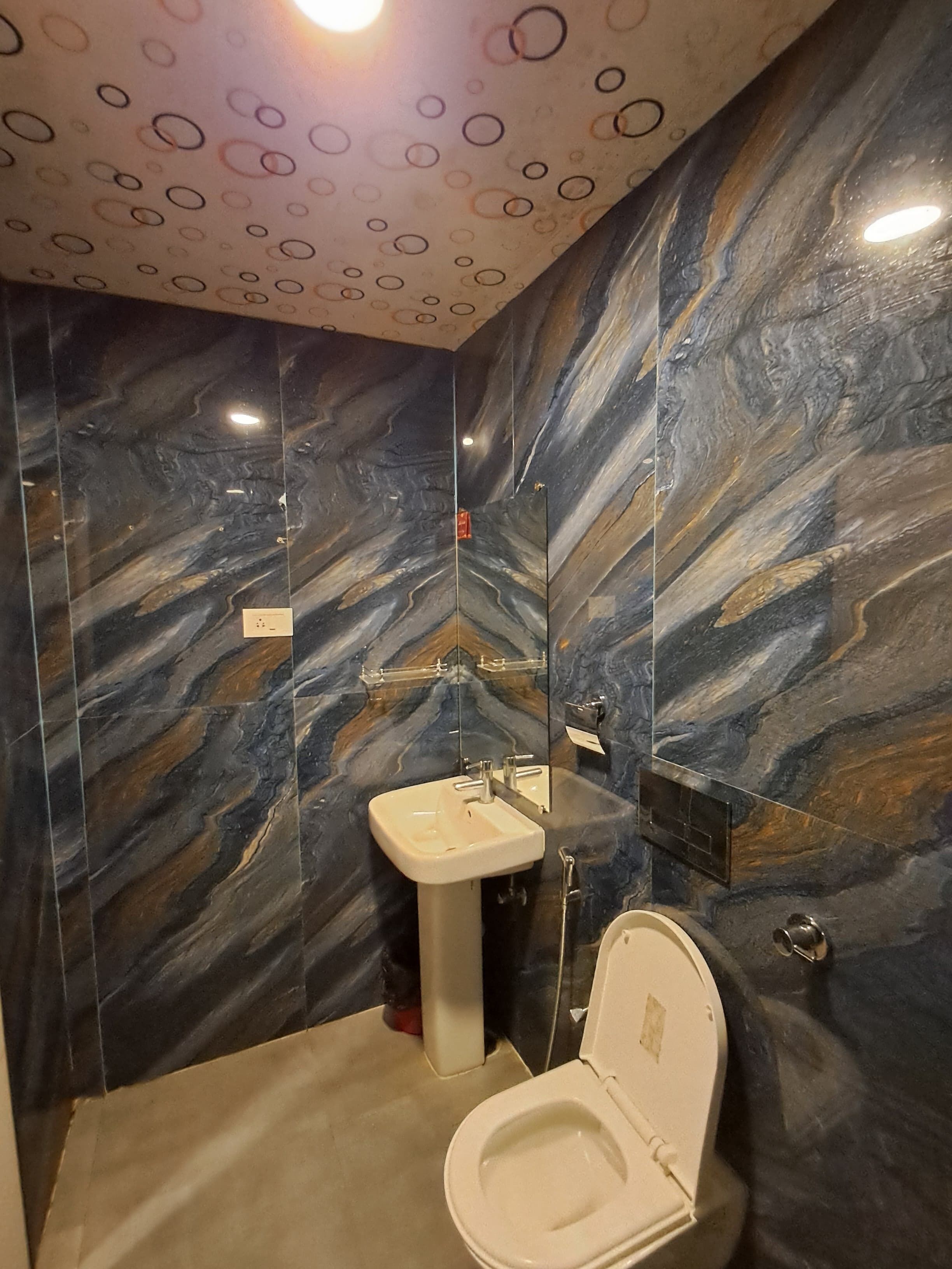 Een badkamer met een marmeren wand, een wastafel en een toilet.