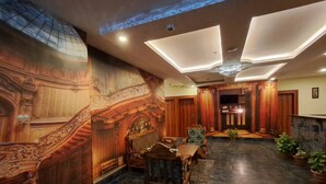 Un'elegante hall con pannelli in legno decorati, una maestosa scalinata e un pavimento in marmo.
