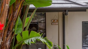 Een gebouw ingang met een 'Beach House' bord, omgeven door tropische planten.