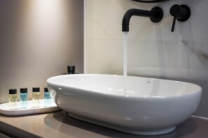 Un lavabo de cerámica blanca con un grifo moderno, una pileta blanca y un dispensador de jabón sobre la encimera.