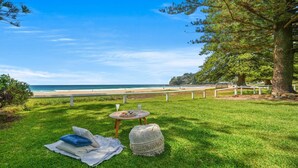 Un'area verdeggiante con un tavolo e sedie, una panchina e vista sulla spiaggia e l'oceano.