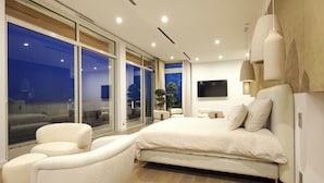 A modern bedroom with a large bed, a sofa, and a TV. - Villa Tigliola (Zonza)