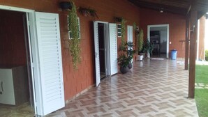 A covered outdoor area with a herringbone-patterned floor, brick walls, and white shutters on doors. - Beautiful farm in Jarinu (Caioçara Jarinu)