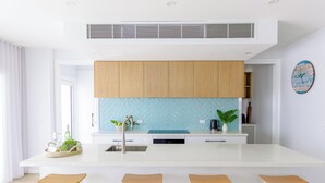 Una cocina moderna con armarios de madera, un salpicadero azul y una isla central con taburetes.