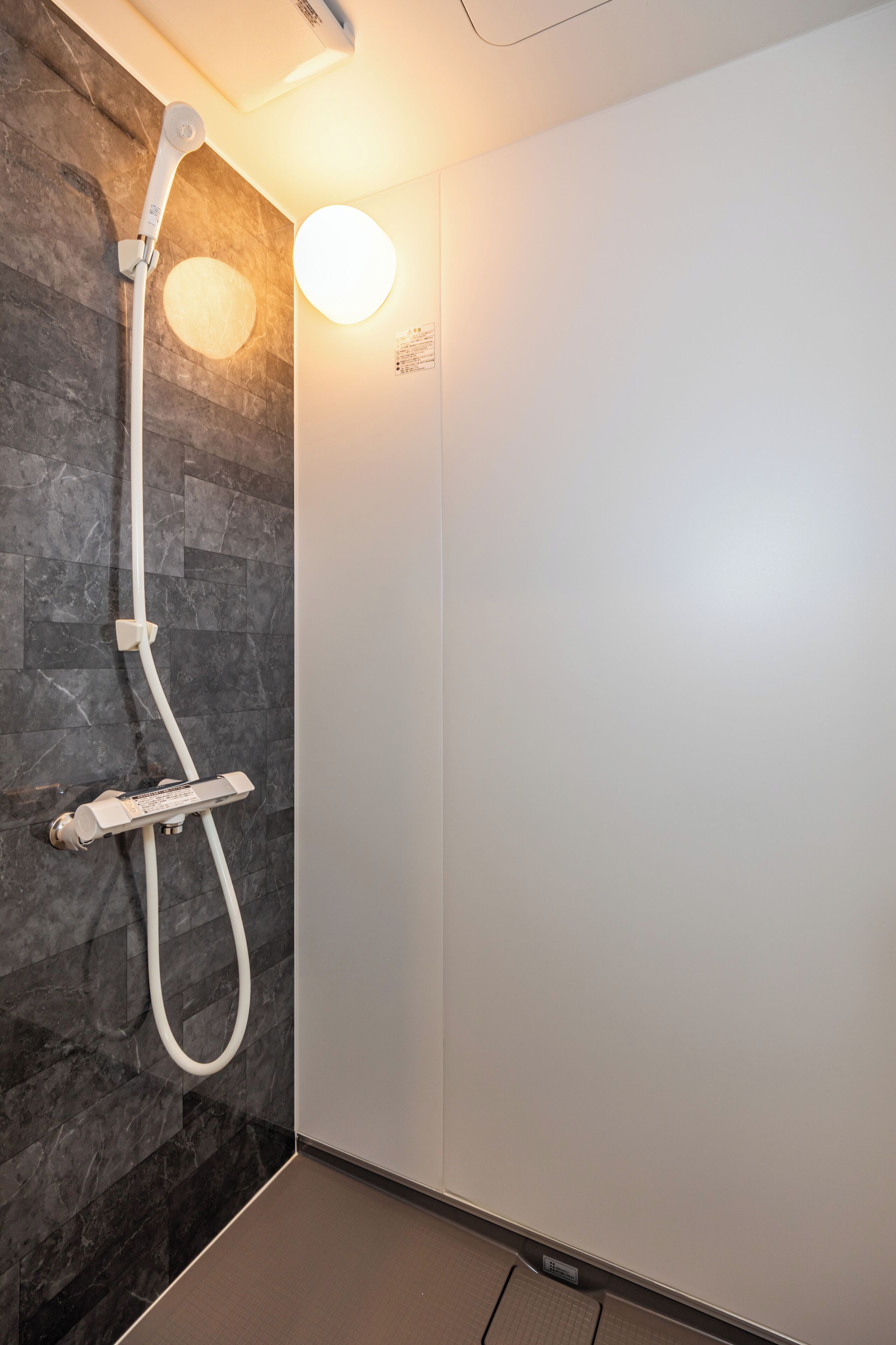A modern shower with a control panel and a handheld showerhead.