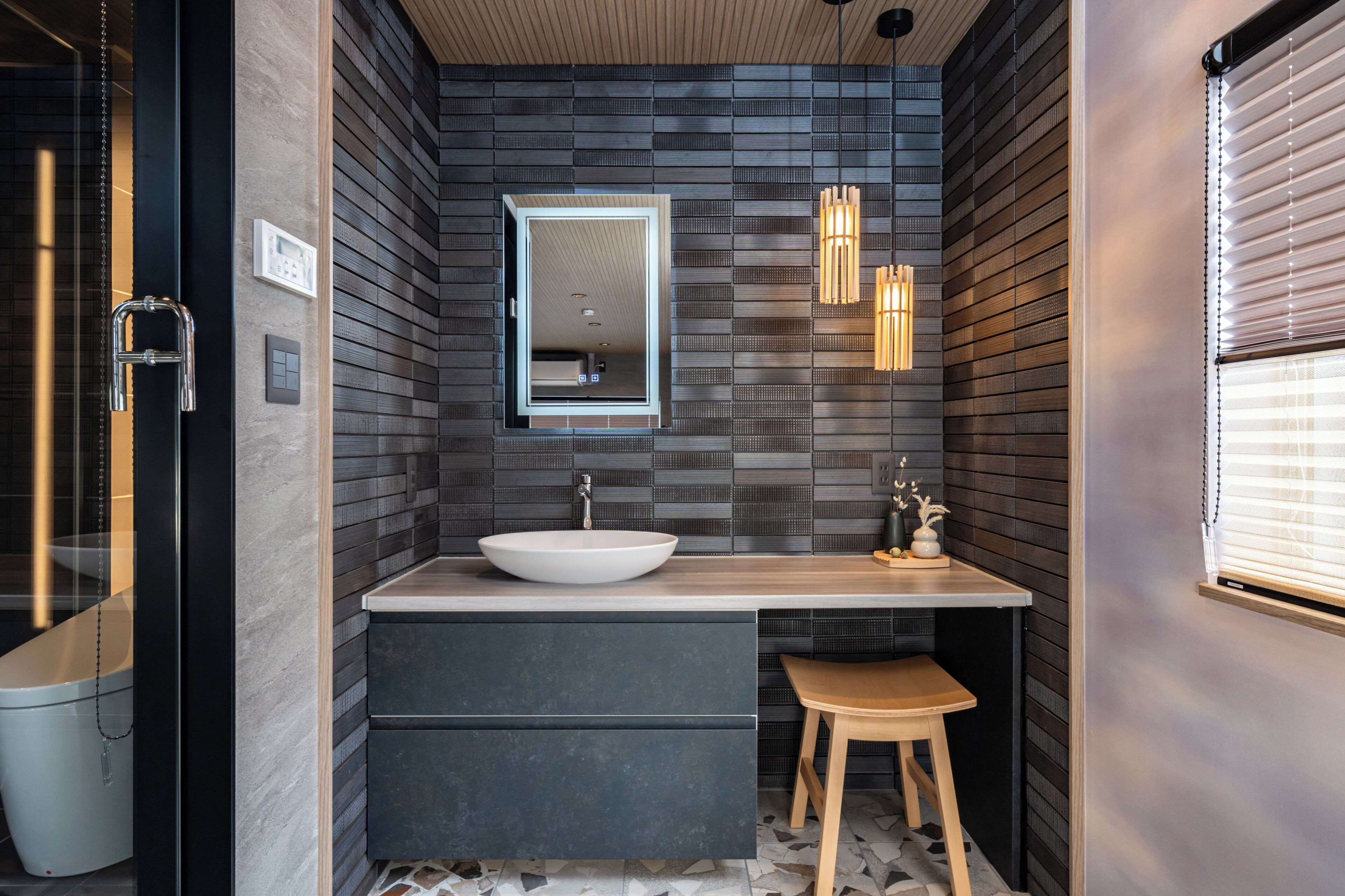 Une salle de bain moderne avec un grand lavabo, un lambris en bois foncé et des luminaires suspendus.