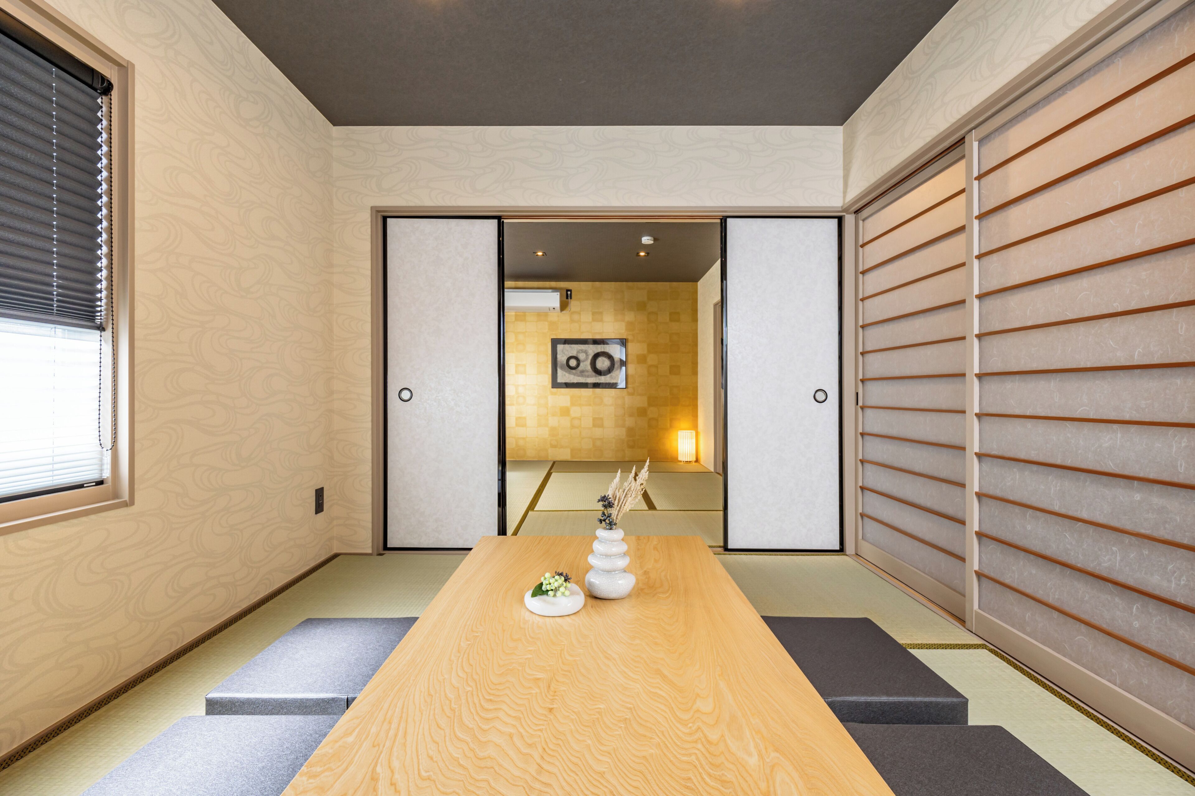 A traditional Japanese room with tatami flooring, a wooden table, and sliding doors.
