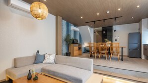 A modern living room with a sofa, coffee table, and dining area with chairs and a table. - JAPAVISTA Yamato (Osaka)