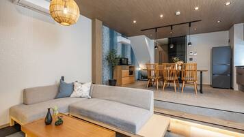 A modern living room with a sofa, coffee table, and dining area with chairs and a table.