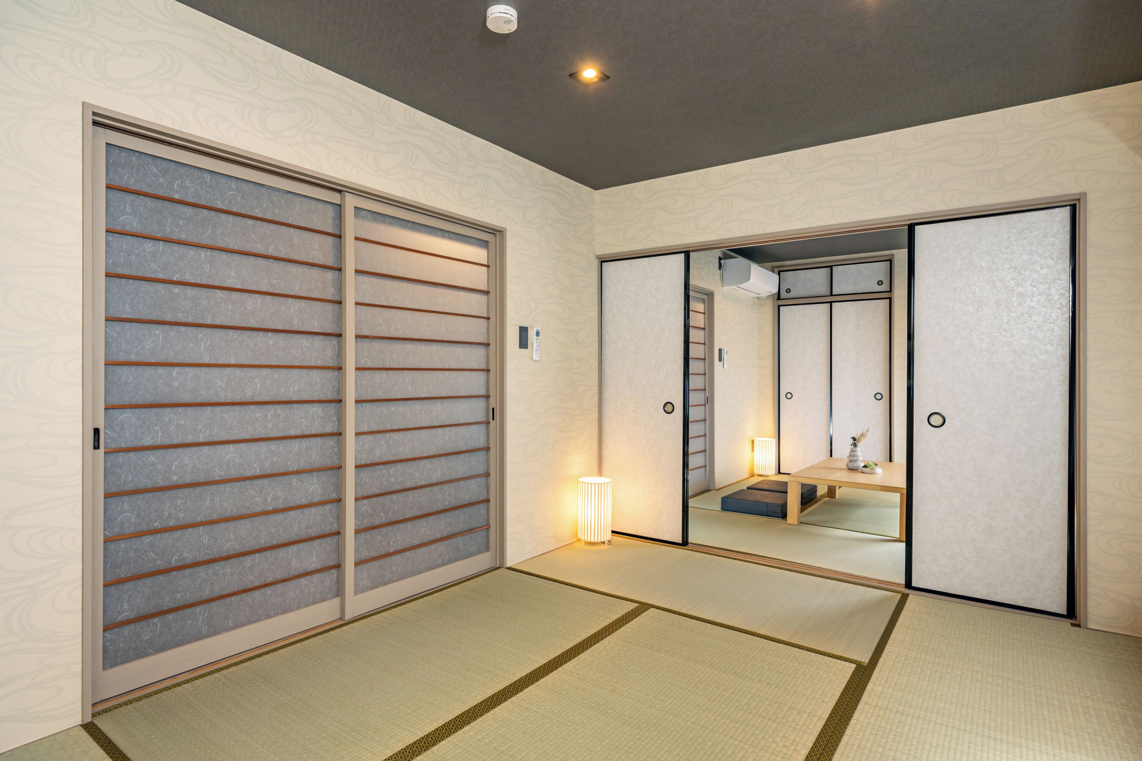 A traditional Japanese room with sliding doors, tatami flooring, and a mirror reflecting the room.