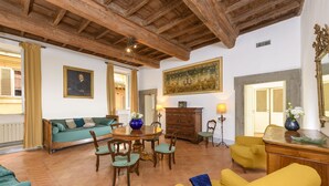 Amplia sala de estar con techo de madera, zona de comedor con mesa redonda y un sillón amarillo.