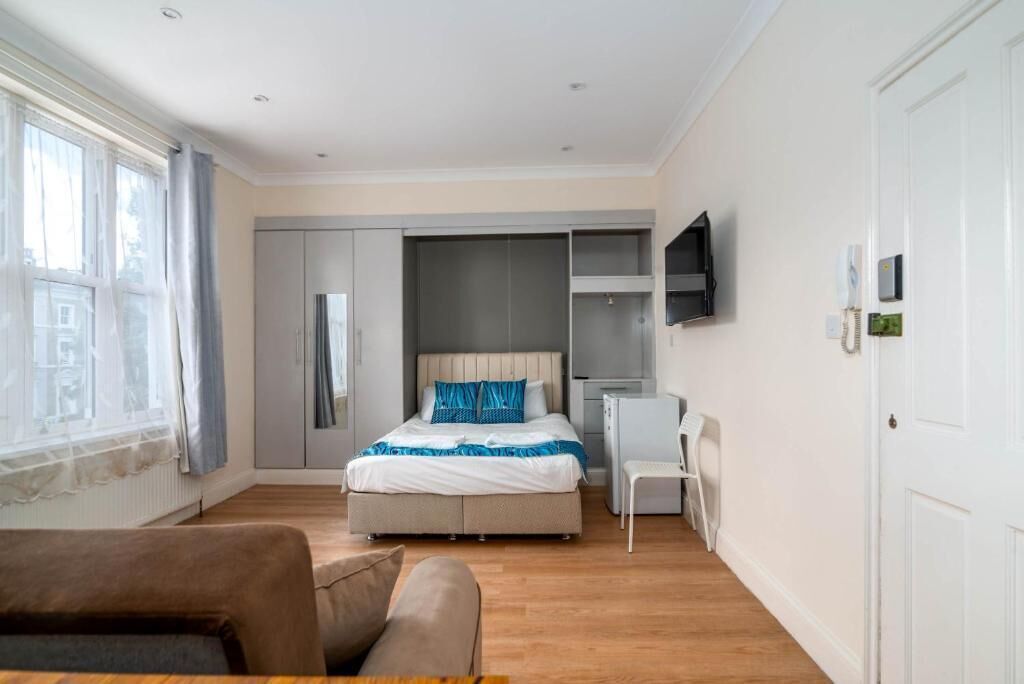 Ein Schlafzimmer mit Bett, Kleiderschrank, Fernseher und Schreibtisch.