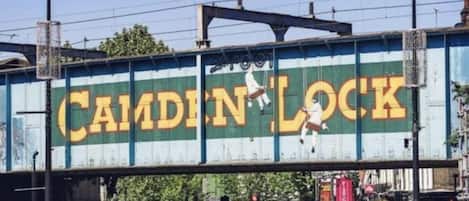 Eine Eisenbahnbrücke mit dem Schriftzug 'CAMDEN LOCK' und einem Radfahrer.