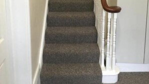 A carpeted staircase with wooden handrails and white walls. - Camden Apartments (London)