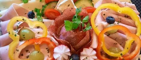 A charcuterie board with various meats, cheeses, and garnishes.
