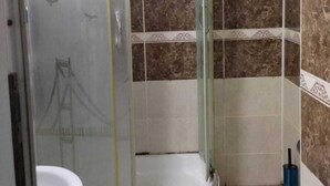 Un baño con cabina de ducha de vidrio, dos lavamanos y paredes con azulejos de diseño marmolado.