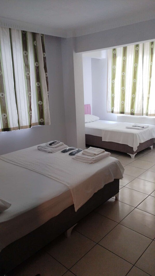 A hotel room with two beds, each with a white bedspread and a neatly folded towel on the bed.
