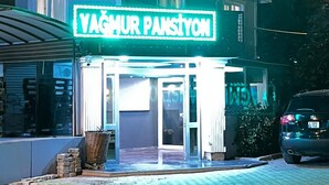 Un edificio con un letrero de neón que dice "YAGMUR PANSTYON" en la entrada.