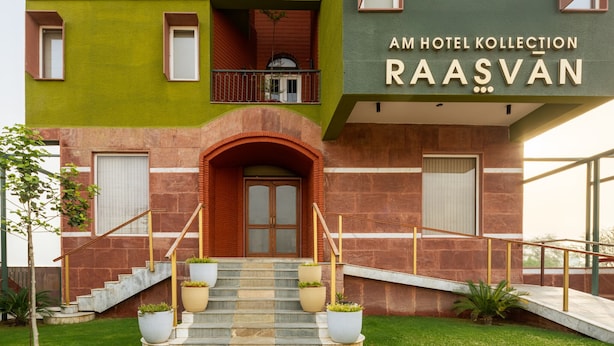 Een hotelentree met een groene gevel, een rode bakstenen boog en een trap naar de ingang.