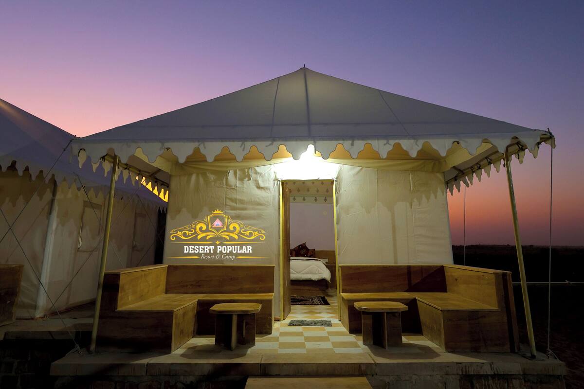 A desert resort tent with a sign reading "DESERT POPULAR Resort & Camp".