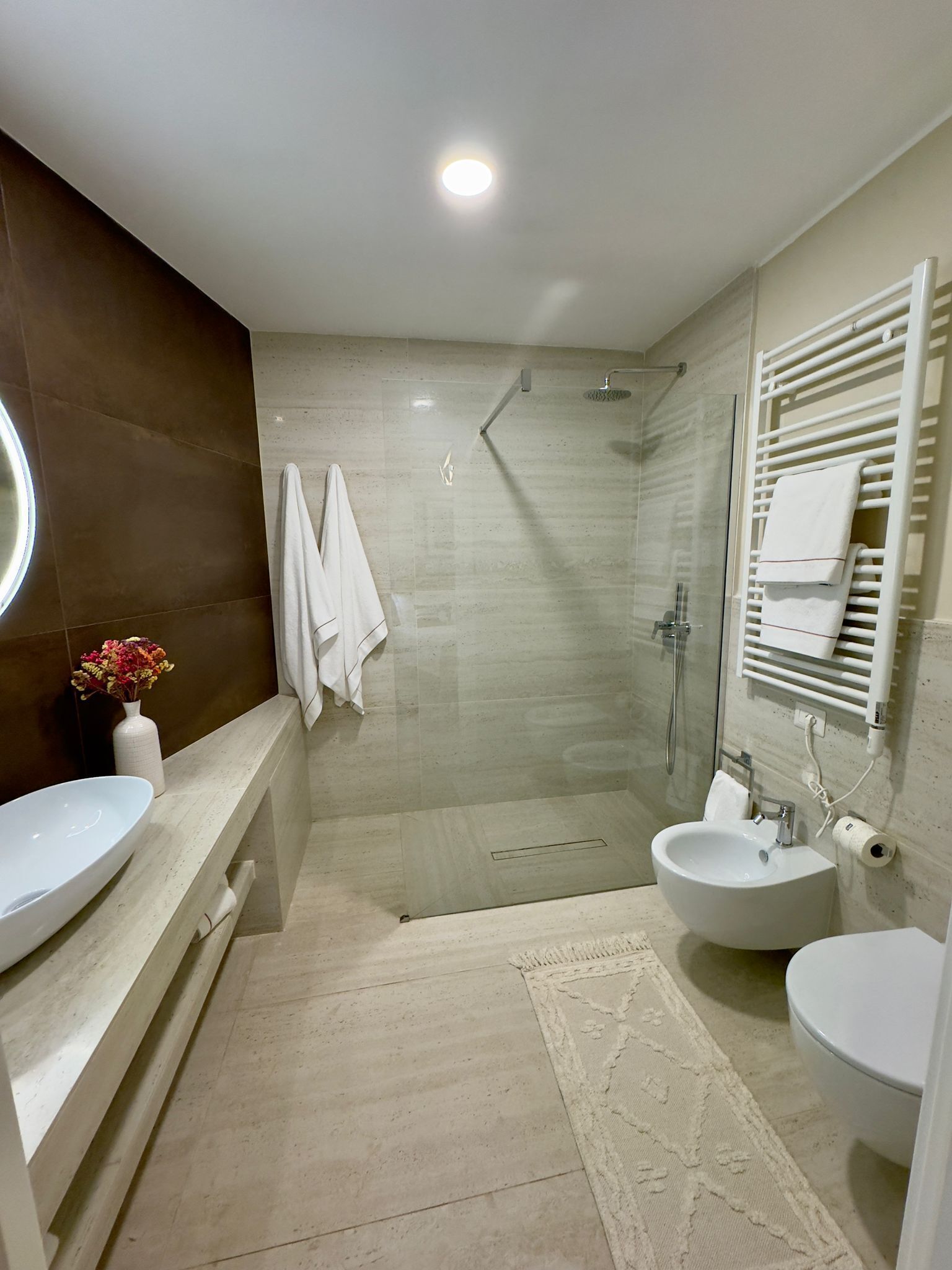 A modern bathroom with two sinks, a shower, and a toilet.