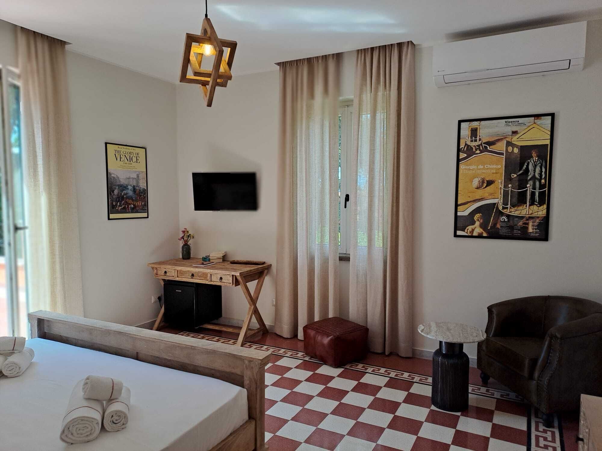 Une chambre d’hôtel avec un lit, un bureau, une chaise, une télévision et un tableau au mur.