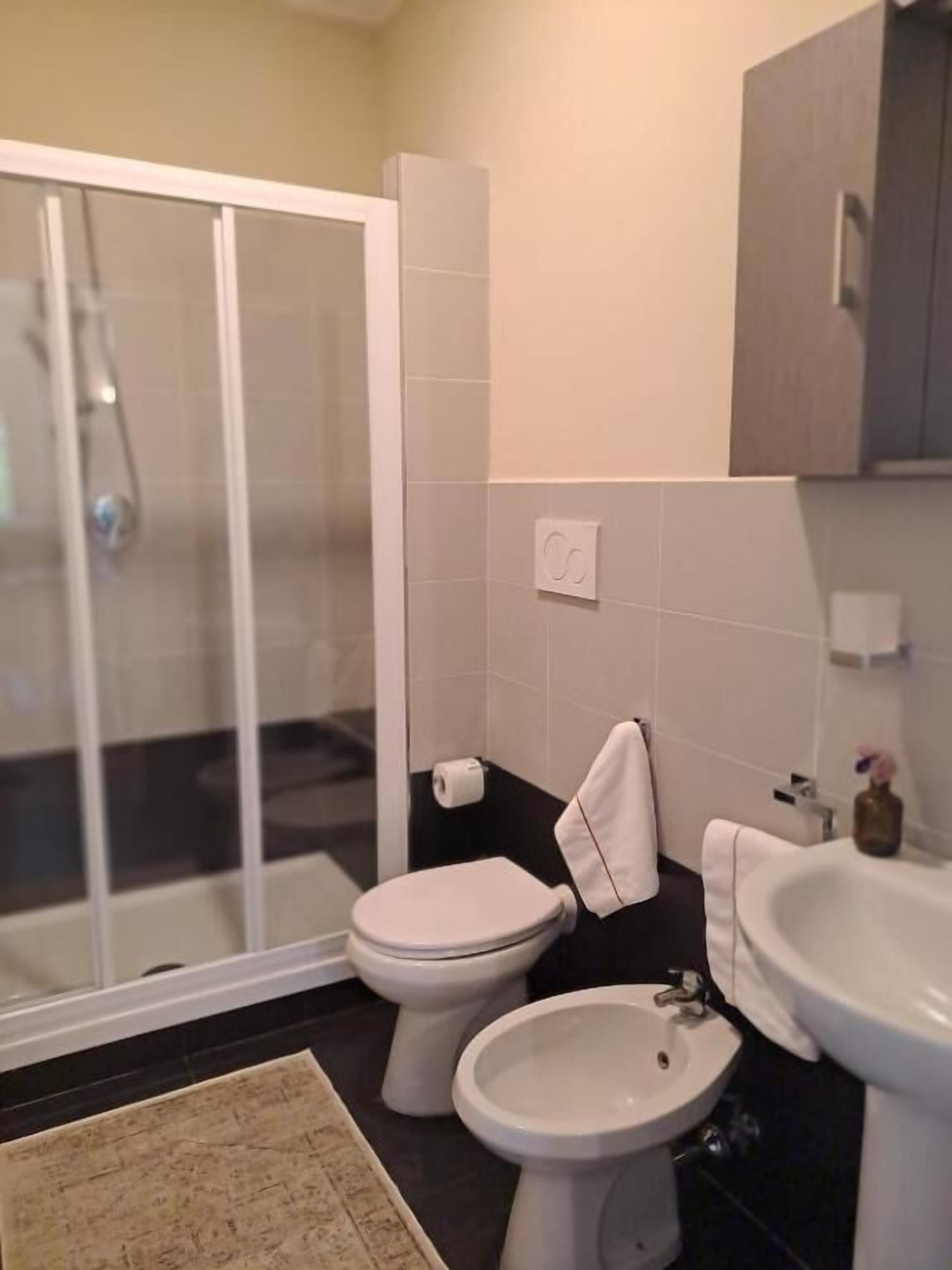 Une salle de bain équipée d’une douche, de toilettes, d’un bidet et d’un lavabo.