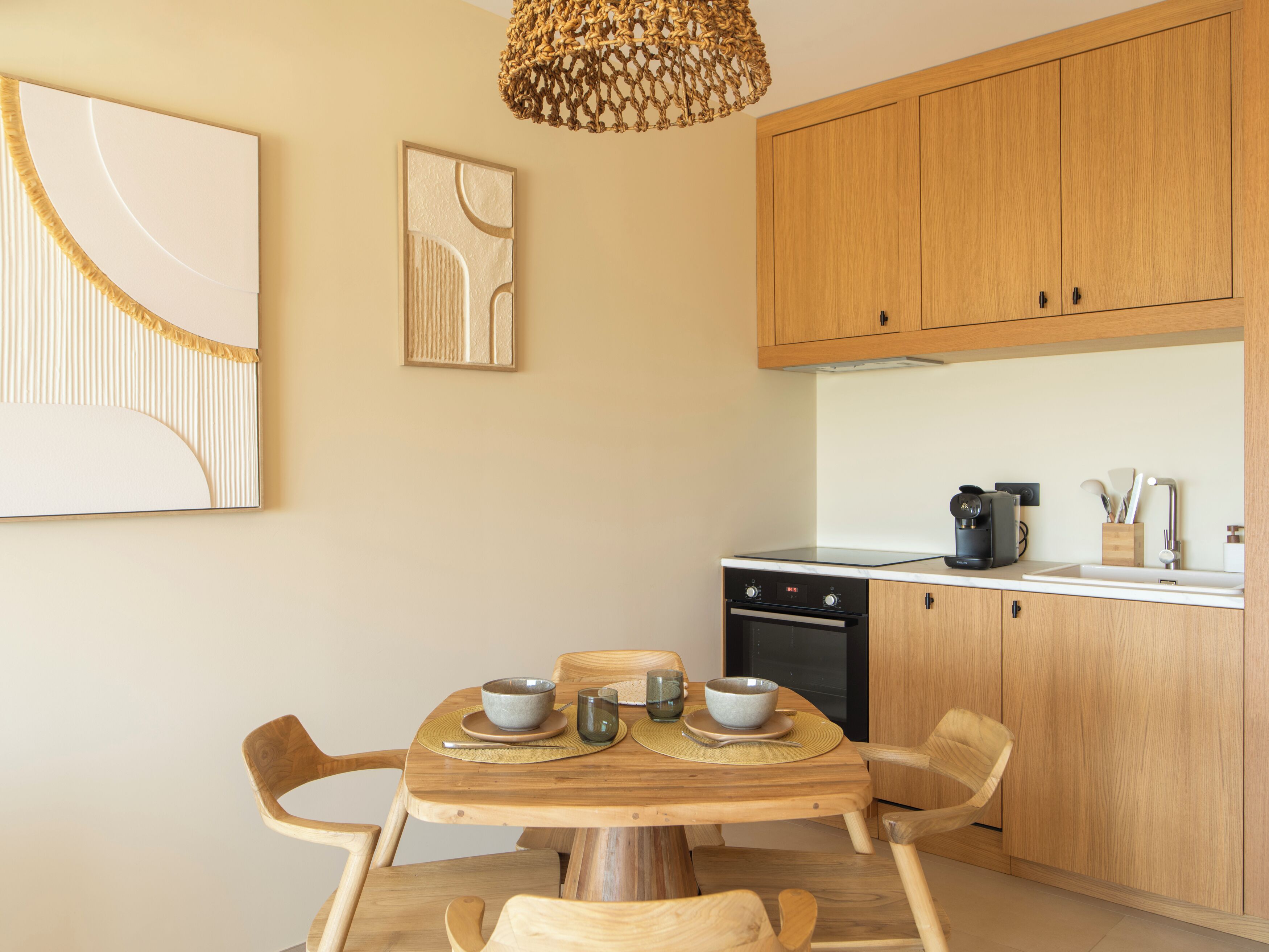 A modern kitchen with wooden cabinets, a built-in oven, and a dining table with chairs.