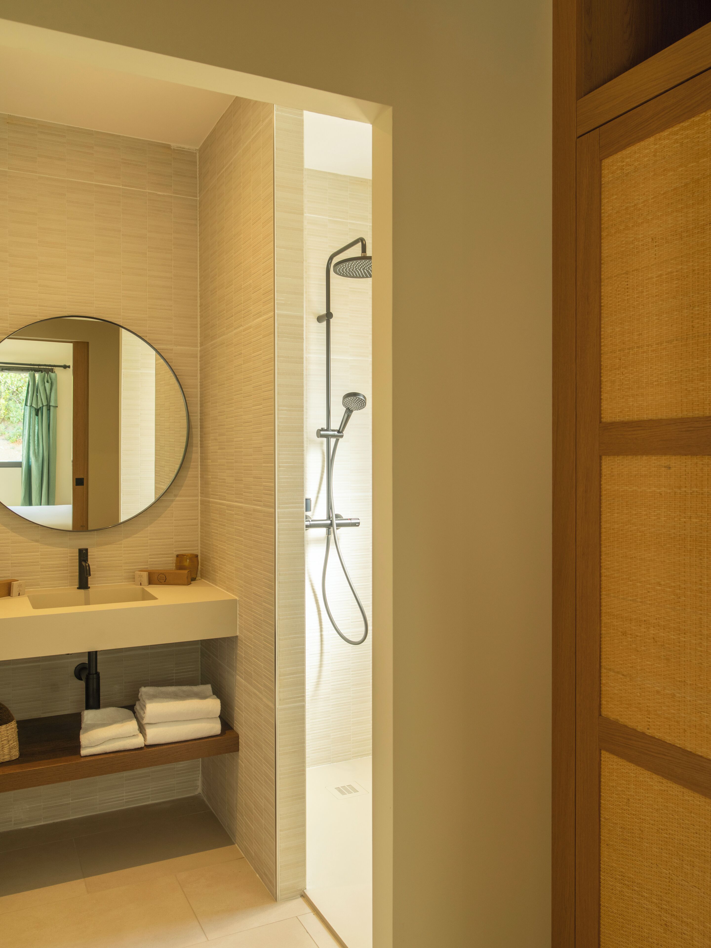 A modern bathroom with a large mirror, a sink, and a shower.