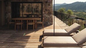 A wooden deck with lounge chairs and a dining area overlooking a mountainous landscape. -  Résidence & Villas Oradoro (Belgodere)